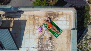 Havlusunu serip, terasta güneşlendi